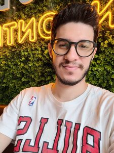 Foto do Lucas com parede verde e letreiro ao fundo