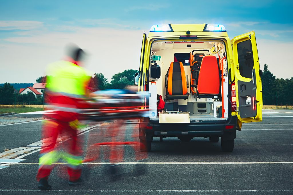 Paramédico levando pessoa com contusão pulmonar de maca para dentro de ambulância