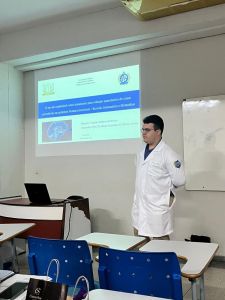 Vinícius de jaleco ao lado de projeção do artigo