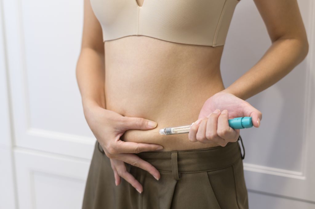 woman using IVF treatment injection on belly to prepare reproductive fertility